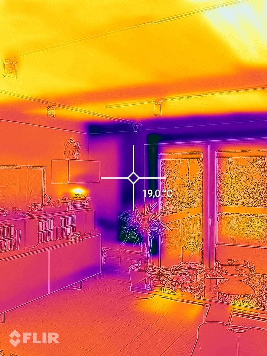 Wärmebild eines Wohnzimmers mit warmer Decke durch die Deckenheizung und einem Messpunkt von 19,0 Grad an der Außenwand neben der Terrassentür.